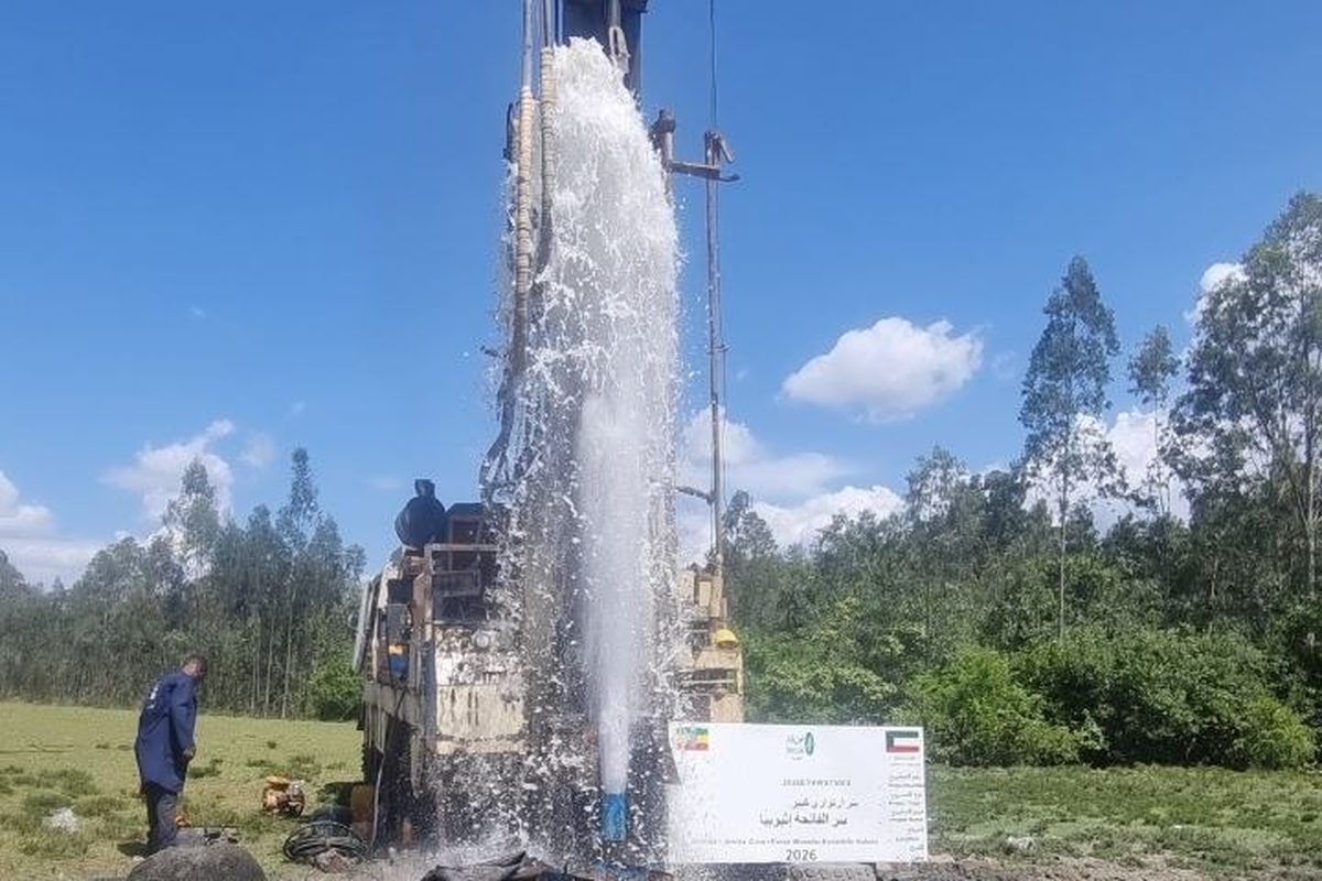 A drilling rig with water spraying from a newly completed borehole during well development